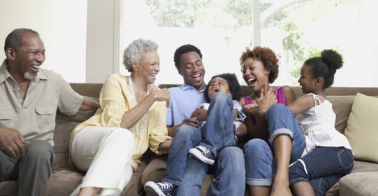 Grandparents, their adult children and their grandchildren laugh together.