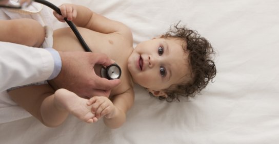 A doctor uses a stethoscope to listen to a baby’s heart.