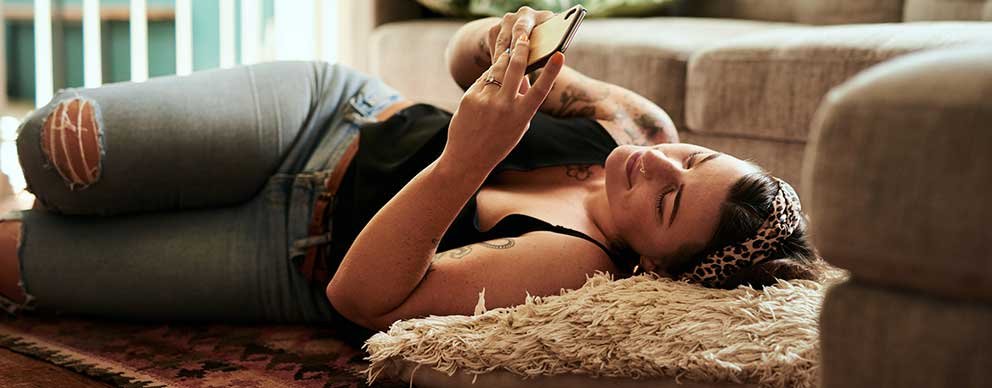 Image of a woman laying on a couch looking at her cellphone