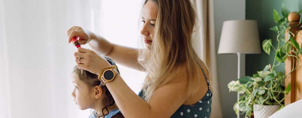 Image of woman combing child's hair